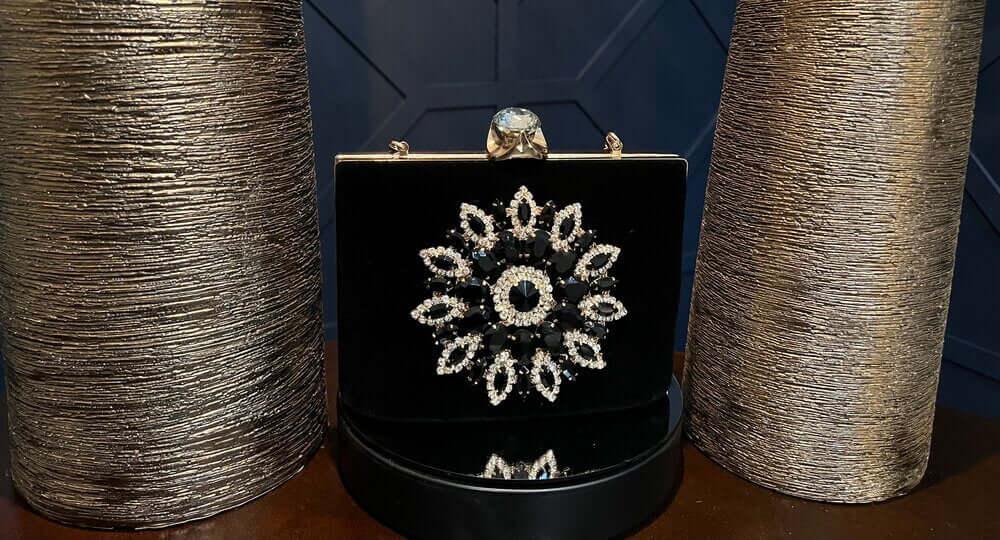 Black velvet clutch with crystal floral design between two textured metallic vases
